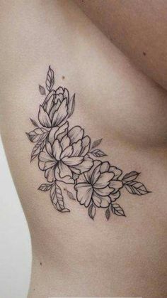 a woman's stomach with flowers and leaves tattoo on her side ribcage