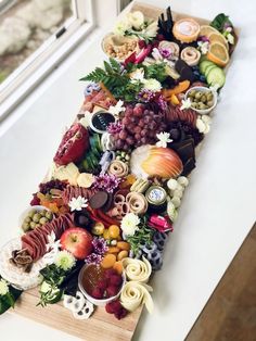 a very long wooden tray filled with lots of different types of food on top of a white counter