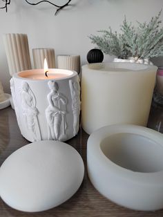 some white candles sitting on top of a table next to vases and other items