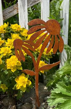 a metal plant with yellow flowers in the background