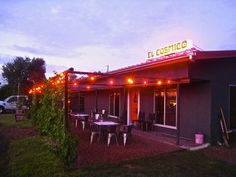 the outside of a restaurant with tables and chairs in front of it at night time