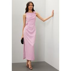 a woman in a pink dress leaning against a wall with her hand on the wall