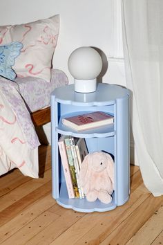 there is a blue shelf with books and a stuffed animal in it on the floor