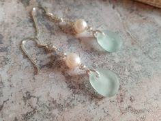 Beautiful frosted white coloured genuine sea glass drop earrings with real pearls encased in .925 sterling silver.  Delicately hand made these droplet earrings are a gorgeous, classy edition to any outfit. Matching necklace: https://www.etsy.com/uk/listing/626387067/sea-glass-necklacewhite-sea-glass-and All my sea glass/beach glass items are hand made from genuine sea glass, that has been tumbling in the sea for 30+ years. My beautifully hand crafted sea glass is lovingly reclaimed from the North Yorkshire Coast and mainly upon the shores of my home town, Saltburn-by-the-sea. As each item is unique, each item is absolutely one of a kind. I only use sterling silver or gold filled materials.  If you would like these in gold please contact me and I can check availability of stock. Returns and Handmade Silver Sea Glass Earrings, Silver Sea Glass Earrings For Gift, Handmade Silver Earrings With Sea Glass, Silver Teardrop Sea Glass Jewelry, Elegant Jewelry With Sea Glass And Ear Wire, Elegant Sea Glass Jewelry With Ear Wire, Elegant Silver Sea Glass Earrings, Silver Sea Glass Drop Earrings, Teardrop Sea Glass Earrings For Gift