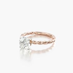 a rose gold engagement ring with a single diamond in the center and a twisted band around it