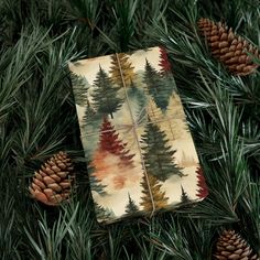 a piece of paper with pine trees on it sitting in the middle of some pine cones