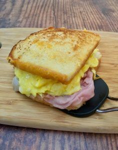 a toasted sandwich with ham and cheese on a cutting board