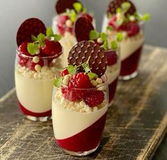 four desserts with strawberries, raspberries and other toppings in small glasses