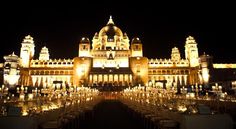 an ornate building lit up at night with many tables and chairs