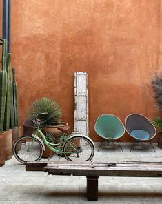 a bike parked next to a bench in front of a wall with potted plants