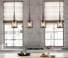 three lights hanging over a kitchen counter next to a stove top oven and window sill