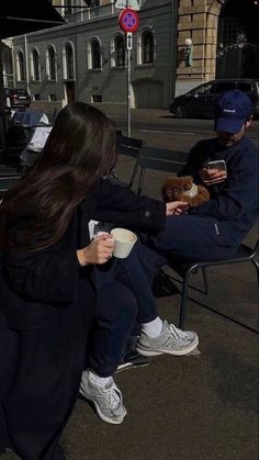 two people sitting on chairs and one is holding a coffee cup while the other holds a teddy bear