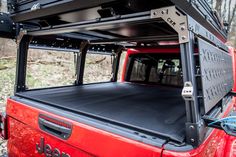 the back end of a red jeep with its roof rack up and cargo compartment open