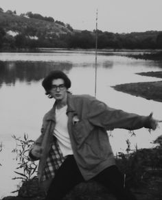 a man standing next to a body of water with a fishing pole in his hand