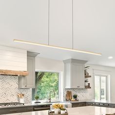 a kitchen with white cabinets and an island in front of a window that looks out onto the trees