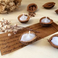 two coconuts with candles in them sitting on a table next to some nuts and flowers