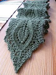 a piece of green crocheted fabric sitting on top of a wooden table next to a rug