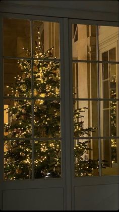 a lit christmas tree is seen through the glass doors of a house in washington, d c