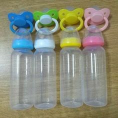 six baby bottles with pacifiers on top of a wooden table