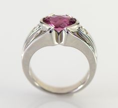 A dazzling pink Tourmaline checkerboard cut from Brazil is is accented with two flush set diamonds in this gorgeous 14k white gold ring. The natural Tourmaline is a 9 x 7 mm oval shape checkerboard cut and weighs 1.93 carats. The two diamonds are round brilliant cuts measuring 2.8mm with a total weight of .16 carats G-H color VS1-2 clarity The ring is 10.5 mm wide (3/8 inch) at the stone tapering down to 3.5 mm The height of the ring is 6 mm Ring weighs 7.31 grams Size 6 3/4 All items from Stowe Modern Tourmaline Wedding Rings, Pink Platinum Ruby Ring For Wedding, Pink Platinum Diamond Ring For Anniversary, Modern Pink Diamond Jewelry, Pink Sapphire Ring In Platinum For Anniversary, Pink Sapphire Platinum Ring For Anniversary, Pink Diamond Birthstone Ring For Formal Occasions, Pink Diamond Birthstone Ring For Formal Events, Pink Diamond Formal Birthstone Ring