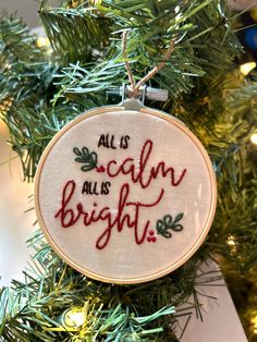 a cross stitch ornament hanging on a christmas tree with the words all is calm and bright