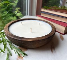 a white candle sitting on top of a table next to a book and some plants