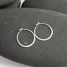 These tiny silver hoops are shaped out of sterling silver or 14K white gold and hammered until they shimmer and shine.  I wanted to make a simple hoop that would be perfect for wearing daily and would be so comfortable that you could forget that you're even wearing them. The posts are tuck into a loop catch on the backside of the earring.This particular pair of earrings from the line is a tiny circle - about 3/4".  Made from responsible and recycled metals - sterling silver and 14K white gold. P Everyday Handmade White Gold Hoop Earrings, Minimalist Hammered Huggie Jewelry, Simple Small Hoop Sterling Silver Jewelry, Handmade White Gold Small Hoop Earrings, Minimalist Hammered Hoop Earrings For Anniversary, Silver Dainty Hammered Hoop Earrings, Hammered Open Circle Hoop Earrings As A Gift, Dainty Hammered Silver Hoop Earrings, Minimalist Hoop Earrings With Sterling Silver Clasp As Gift