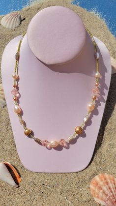 A beautiful necklace laying upon sand and shells as if it were on a sunny beach. The necklace is handmade by brand Gypsy Caravan Design and includes colored fresh water pearls, peach colored Czech glass beads and delicate green seed beads to resemble sunlit seaweed from under the sea. Bohemian Single Strand Pearl Jewelry, Bohemian Pearl Necklaces For Jewelry Making, Adjustable Bohemian Pearl Drop Necklaces, Bohemian Single Strand Pearl Necklace, Bohemian Gold Beaded Necklace With Pearl Drop, Gold Bohemian Single Strand Pearl Necklace, Bohemian Pink Czech Glass Beaded Necklaces, Bohemian Pearl Beaded Necklaces, Bohemian Beaded Necklaces With Pearl Drop For Gifts