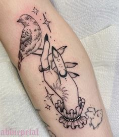 a woman's arm with a bird on top of it and stars around her