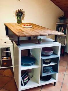 a kitchen island with plates and bowls on it in front of a potted plant