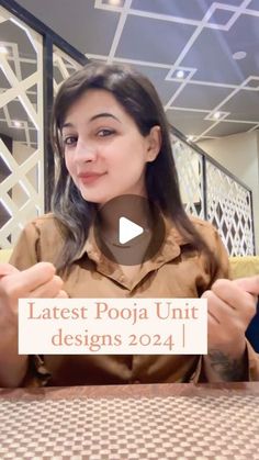 a woman sitting at a table with a sign in front of her that says latest poja unit designs 2014