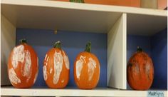 three orange pumpkins sitting on top of a white shelf