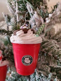 a starbucks cup ornament hanging from a christmas tree with white frosting on it