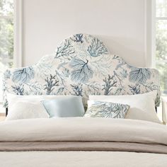 a bed with blue and white coral print headboard