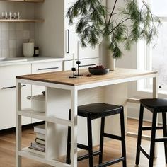 two stools sit at a kitchen island with a potted plant in the center