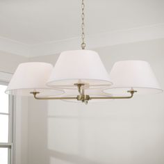 a chandelier with three white lamps hanging from it's sides in a living room