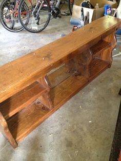 a wooden bench sitting inside of a garage next to a pair of bicycle's