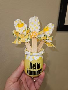 a hand holding a cup with flowers and lemons in it that says hello summer