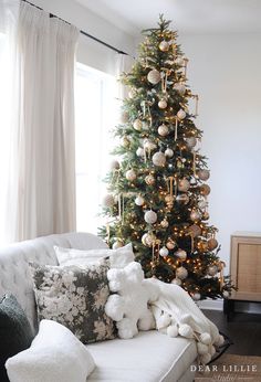 a living room with a christmas tree in the corner and pillows on the couches