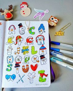 an open notebook with stickers and markers on the cover, next to some pens