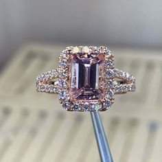 an engagement ring with a pink diamond surrounded by white and brown diamonds on a stick