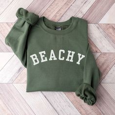 This Beachy Sweatshirt is the perfect gift for the beach lovers in your life! It features the trendy varsity style that will be loved for years to come!  This unisex, heavy blend crewneck sweatshirt is pure comfort and will quickly become your go-to. COLOR: This Gildan 18000 sweatshirt comes in several colors, look at the drop down for options.   SIZING: These sweatshirts are UNISEX in size.  Please check the size chart in listing photos for best fit!   MATERIAL:  -Made from polyester and cotton with a ribbed knit collar, it retains its shape even after washing. There are no itchy side seams on these sweaters and the tag is tear-away.  -Using a medium-heavy fabric blend of 50% cotton and 50% polyester, this sweatshirt feels cozy and is the perfect choice for those colder months. -100% ethi Trendy Letter Print Sweatshirt For Beach, Letter Print Sweatshirt For Beach Vacation, Beach Season Sweatshirt With Letter Print, Trendy Cotton Sweatshirt For Beach, Cotton Sweatshirt With Letter Print, Cotton Sweatshirt For Beach Vacation, Cotton Sweatshirt For Beach Season Vacation, Trendy Crew Neck Sweatshirt For Beach, Green Sporty Top For Beach Season