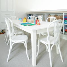 a white table and chairs in a room with toys on the shelves behind it,