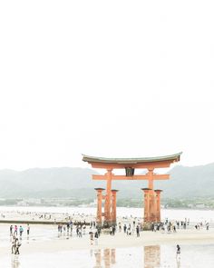 people are walking on the beach in front of a large tori tori shrine at low tide