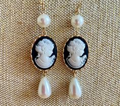 An ultra-feminine flirty pearl cameo dangle earring with a pearl up top and a teardrop pearl at the bottom: a beautiful white cameo on a jet black background in a gold frame, guaranteed to get compliments this season! We want you to look beautiful, but keep your savings account, too: Our U.S. FREE SHIPPING guarantees your jewelry budget isn't eaten up by postage.  Queen Victoria's love for cameos significantly increased their popularity in the 19th century as they became symbols of status and el Taylor Tomasi Hill, Black Cameo, Bridesmaids Earrings, Astoria Ny, Cameo Earrings, Vintage Style Earrings, Ultra Feminine, Cameo Jewelry, Fashion Institute