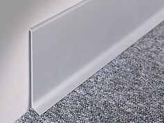 a close up view of the corner of a white wall and carpeted flooring