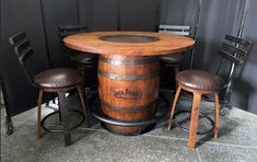 a wooden barrel table with stools around it