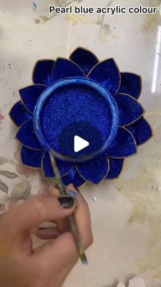 a person is painting a blue flower with acrylic paint