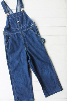 Vintage denim dungarees in blue. Single chest pocket and double waist pockets front and back. Tapered leg. UK 6 / EUR 34 Measurements - 30"(76cm) waist - 32"(81cm) hips - 21"(53cm) inner leg. Material - Denim. Condition - Excellent. Handpicked, repaired and ready to wear. This is an original vintage item, not new and minor signs of wear & age are expected, we will highlight any major flaws. Model is a UK 8 and is 5'6" tall. Vintage Denim Jeans With Side Pockets, Medium Wash Bib Front Jeans For Work, Blue Utility Overalls With Straight Leg, Blue Utility Straight Leg Overalls, Blue Straight Leg Utility Overalls, Vintage Denim Bottoms With Side Pockets, High Waist Denim Blue Overalls With Pockets, Utility High Rise Overalls With Pockets, Denim Bib Front Jumpsuit With Pockets