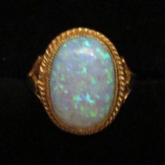 An oval-created opal Ring set in an 18ct Gold and Silver rope edge setting and Shank. Beautifully hand-made by a British professional Jewellery craftsman to the highest standard. Classic Oval Opal Ring Collectible, Heirloom Oval Opal Ring Collectible, Heirloom Oval Cabochon Opal Ring, Antique Oval Opal Gemstone Ring, Antique Oval Opal Ring, Oval Opal Cabochon Ring, Heirloom Oval Opal Ring Hallmarked, Antique Oval Opal Collectible Ring, Handmade Oval Opal Ring In Yellow Gold